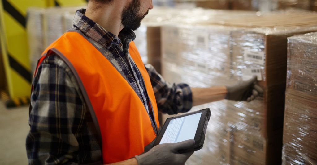 warehouse worker inspecting items while holding a Getac rugged tablet